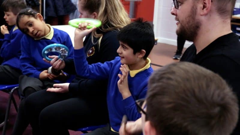 A group of children is learning about sound and silence at a music workshop.